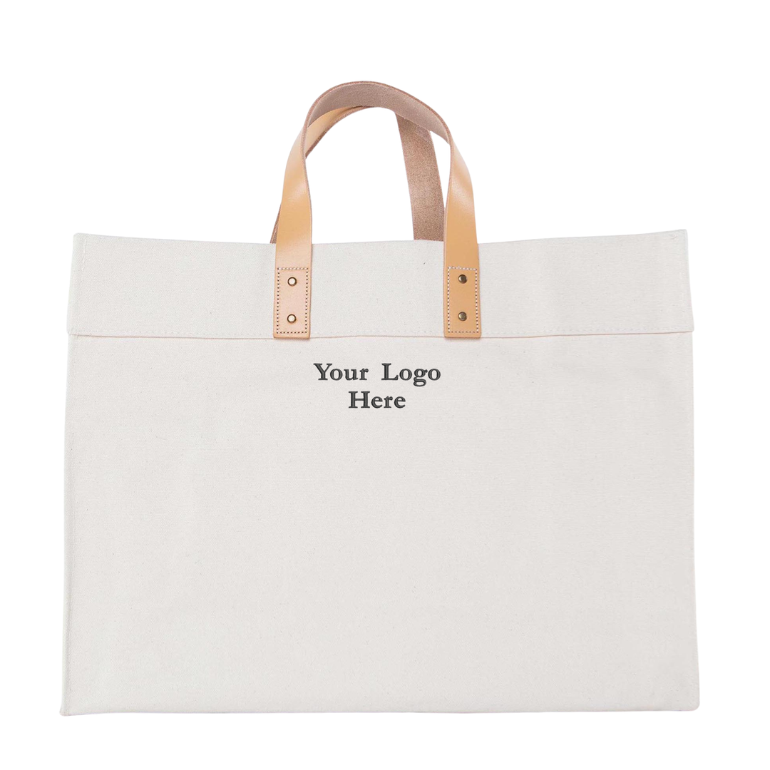 Natural canvas tote bag with tan leather handles and customizable logo area on front panel.
