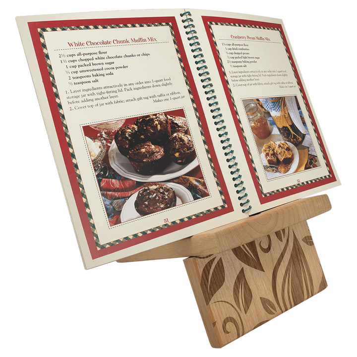 Large stand holding an open cookbook, with an engraved leaf design on the base
