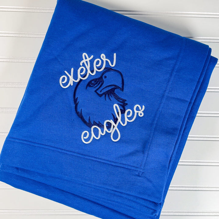 Royal blue fleece blanket with "Exeter Eagles" text and eagle mascot logo in white and navy embroidery