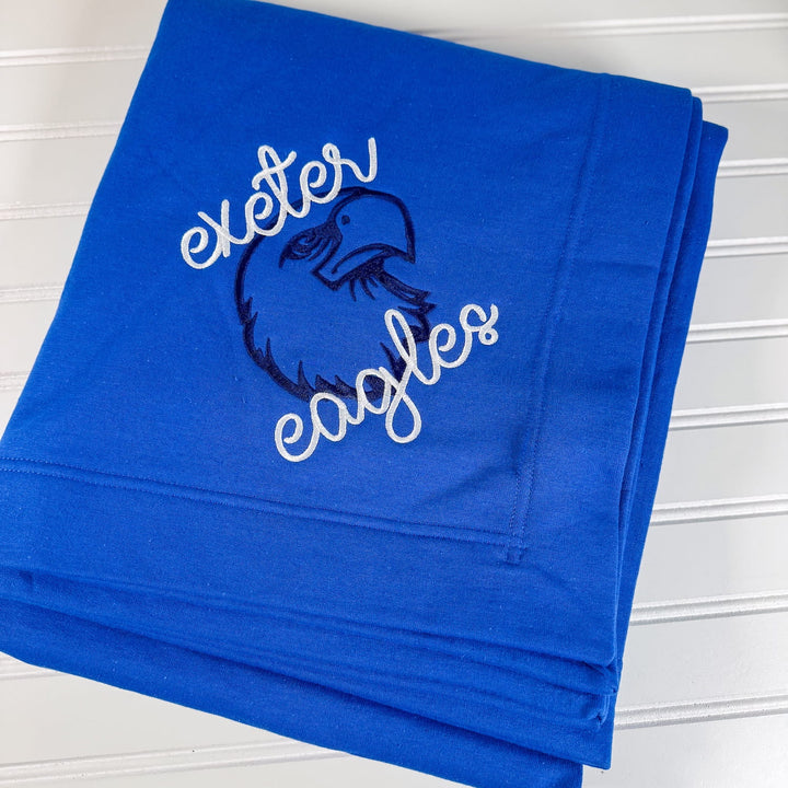 Royal blue fleece blanket embroidered with "Exeter Eagles" text and eagle mascot logo in white and navy.