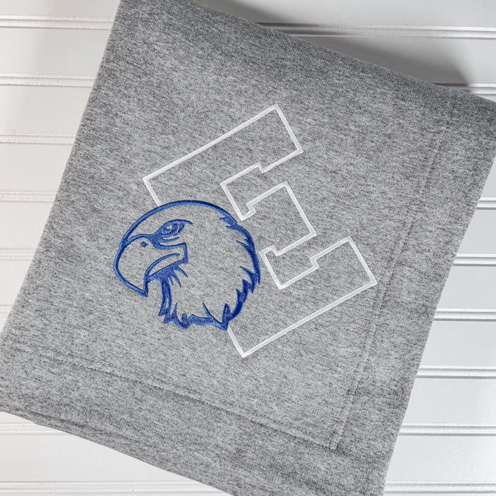 Grey fleece blanket with blue embroidered eagle head and white varsity letter patches.