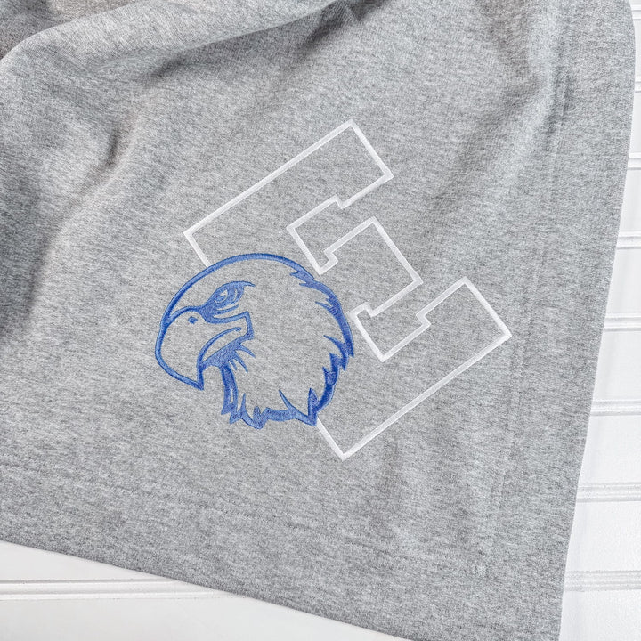 Heather grey fleece blanket with blue embroidered eagle head mascot and white varsity letter patches