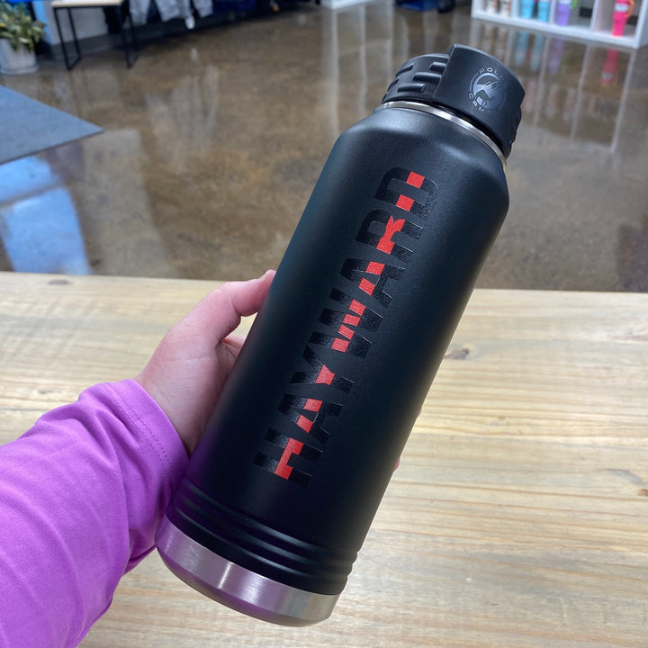 Black water bottle with red "Thin Red Line" text, held in hand wearing purple sleeve
