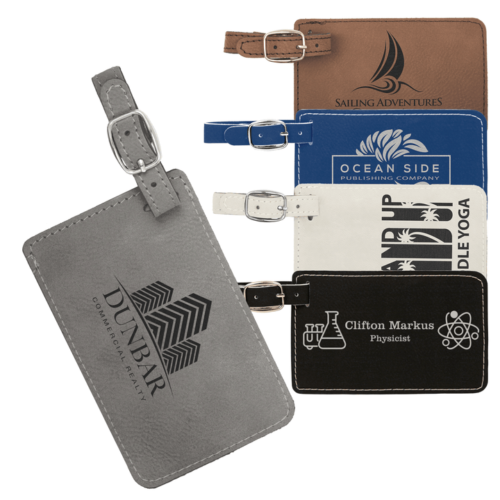 Stack of custom luggage tags in various colors including gray, blue, cream, and black with embossed logos and attached straps.
