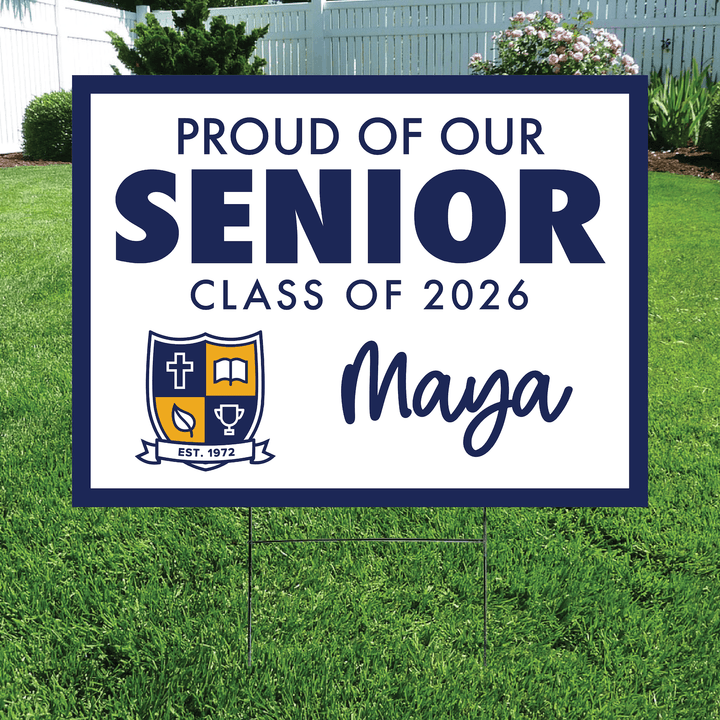 Navy and white yard sign reading "Proud of Our Senior Class of 2026 Maya" with school crest logo, displayed on grass with stake.