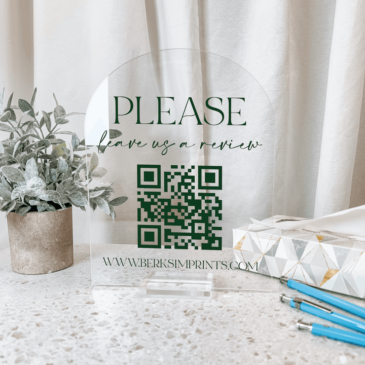 Clear acrylic sign with "PLEASE leave a review" text and green QR code, featuring www.berksimprints.com website URL.