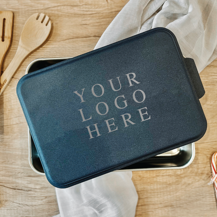 Navy blue cake pan with customizable logo text area, displayed on wooden surface with kitchen utensils