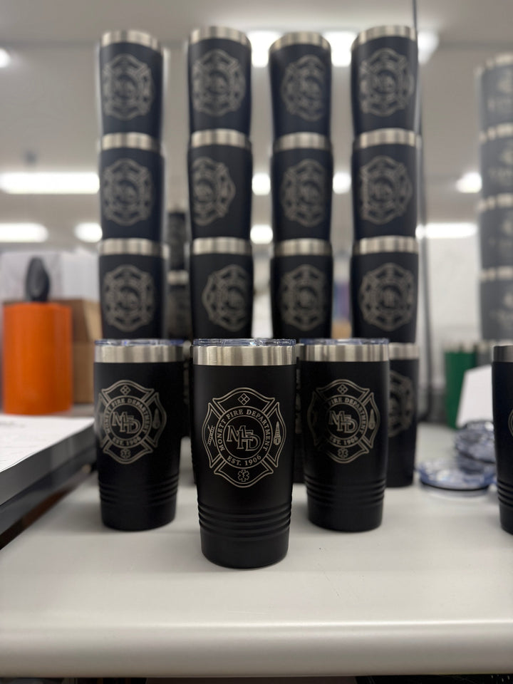 Stacks of black tumblers engraved with a fire department Maltese cross patch