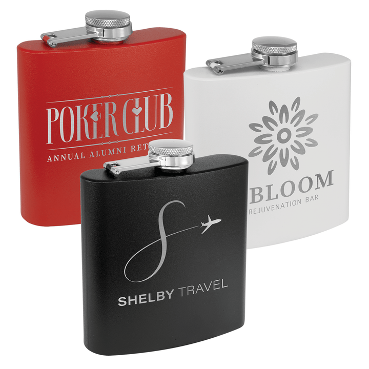Three powder coated stainless steel flasks in red, white, and black with custom laser-engraved logos for Poker Club, Bloom, and Shelby Travel.